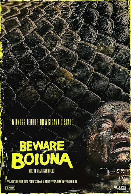 Movie poster for Beware Boiúna. A massive coil of dark green snake scales fills the frame above murky water. At the lower right, a person's mud-streaked face breaks the surface, mouth open mid-scream, eyes wide. The tagline "Witness terror on a gigantic scale" runs above the title, which appears in jagged yellow capitals. Only in theaters October 2.