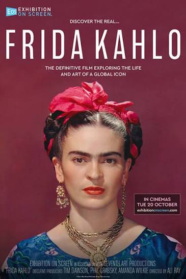 Movie poster for Frida Kahlo. A color portrait photograph shows Frida Kahlo looking straight ahead, with a bright pink ribbon woven into her braided hair, red lipstick, gold earrings, and layered gold necklaces over a blue blouse, against a deep plum background.