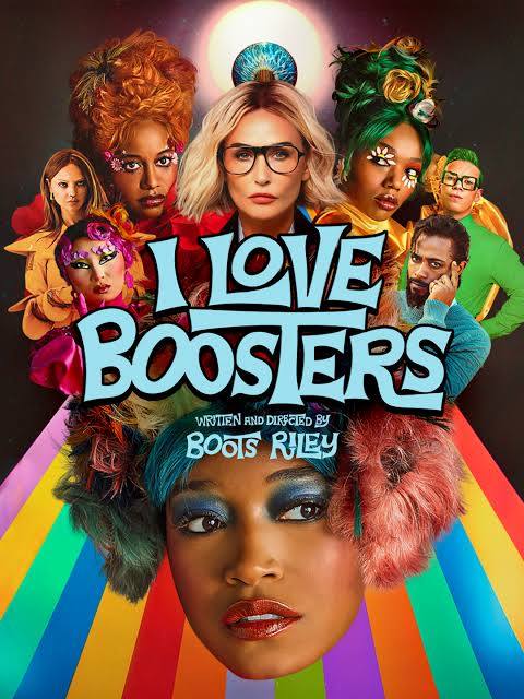 Poster for I Love Boosters. A large-scale collage of characters with vivid, stylized hair and makeup with fun greens, magentas, and platinum blonde, all clustered around a glowing blue orb at the top; below them, a woman's face in close-up with teal eyeshadow, glossy orange lips, and a shaggy multicolored fur collar. Rainbow stripes radiate outward behind her. Title text in pale blue block letters reads "I Love Boosters," with "Written and Directed by Boots Riley" beneath.
