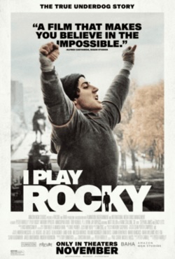 Movie poster for I Play Rocky. A man portraying Sylvester Stallone, in a gray sweatsuit and knit cap, raises both fists overhead in triumph on a city street. A statue on a pedestal stands behind him. The title appears in white capitals. Tagline: “The true underdog story.”