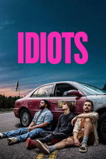 Movie poster for Idiots. Three young men sit on the ground leaning against the front of a maroon sedan parked on a roadside at dusk, one holding a can. The title appears in large pink capitals at the top.