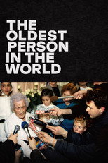 Movie poster for The Oldest Person in the World. A very old woman with white hair sits surrounded by a crowd of about eight people, several of them small children leaning in close. A cluster of microphones is held toward her at the lower right. The title appears at the upper left in white capitals on black.