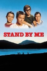 Movie poster for Stand By Me. Four boys stand grouped together against a blue sky above the title in red block letters. Below, the same four are shown in silhouette walking single file along a ridge, with dark hills and a lake behind them.