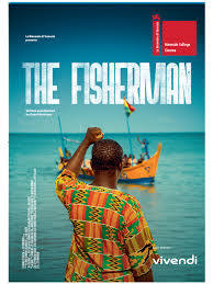 Movie poster for The Fisherman. A man in a patterned green and yellow shirt stands with his back to the camera on a beach, one arm raised, facing a blue and yellow boat in shallow water under a pale sky. A small flag flies from the boat. The title appears at the upper left in white capitals.