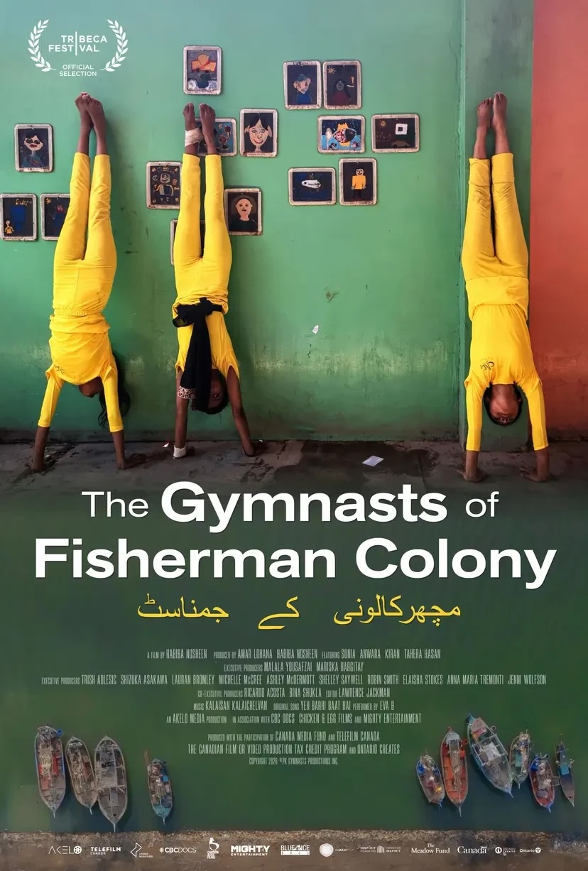 Movie poster for The Gymnasts of Fisherman Colony. Three girls in yellow outfits do handstands against a weathered green wall hung with children’s drawings. Along the bottom, small fishing boats are seen from above on dark green water. The title appears in white, with an Urdu version in yellow beneath it.